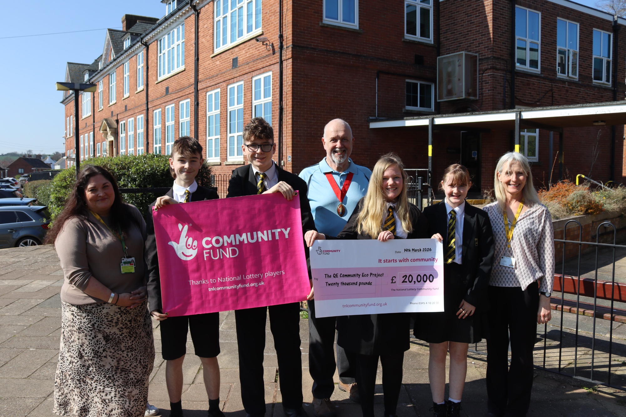 Students and staff stood outside QE School holding a large cheque for £20,000 National Lottery Grant