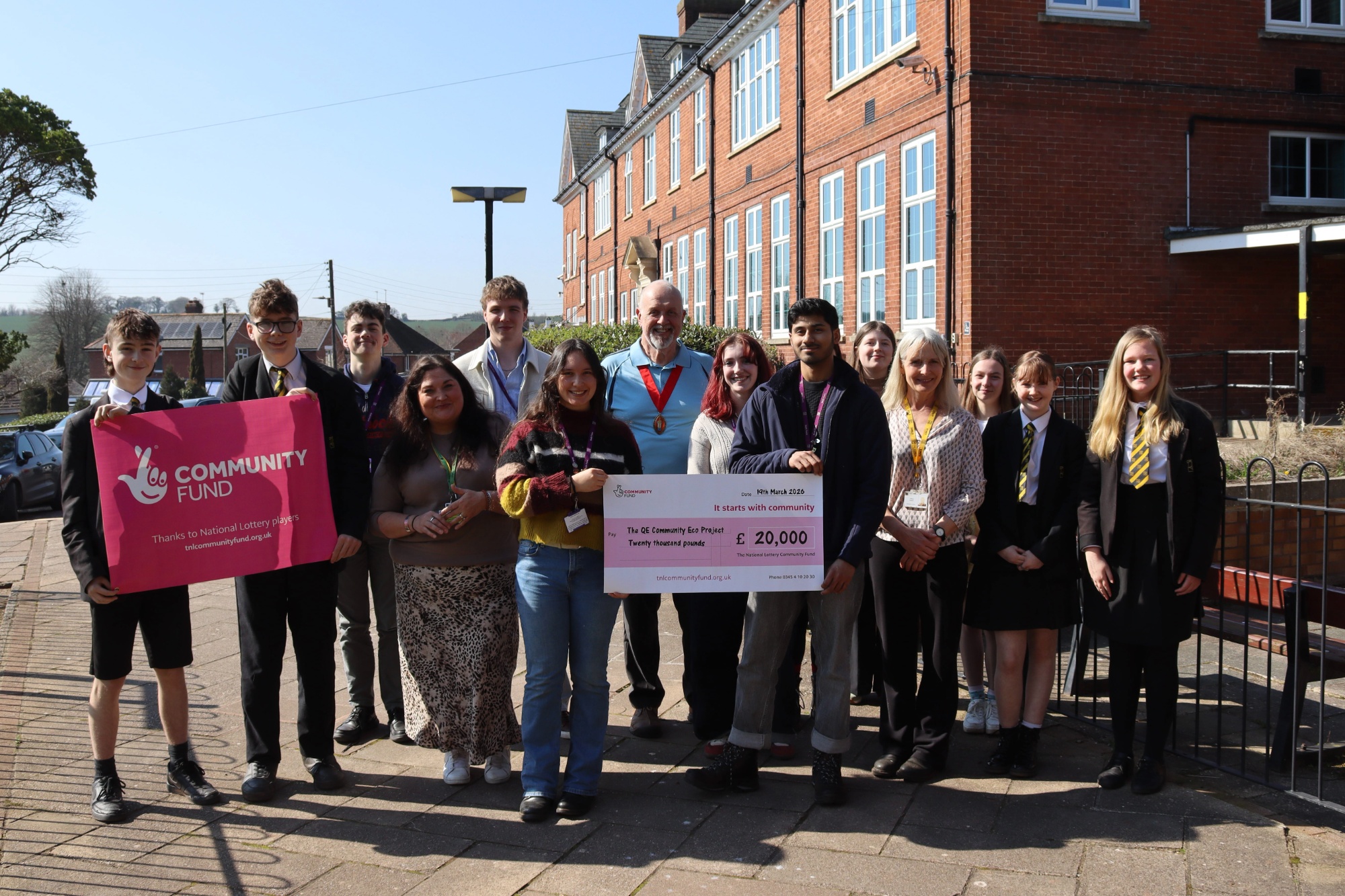 Students and staff stood outside QE School holding a large cheque for £20,000 National Lottery Grant